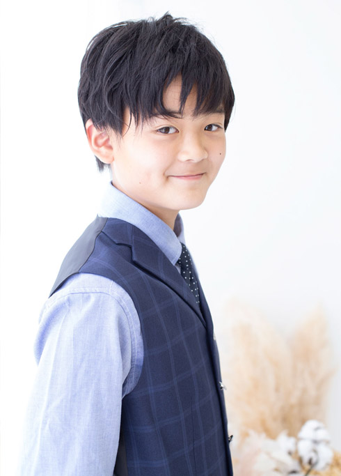 ハーフ成人：水色のシャツにチェック柄の濃紺ベストとネクタイを合わせた10歳の男の子