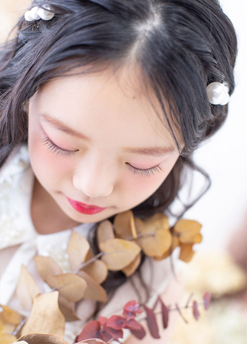 ハーフ成人：白の襟付きドレスを着てトレンド感あるメイクを施した、10歳女の子の顔