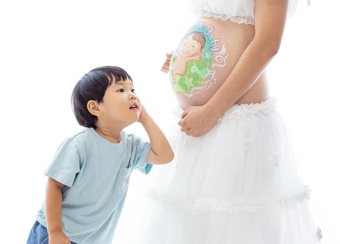 マタニティ：ベリーペイントを施したママのお腹に耳を傾ける男の子