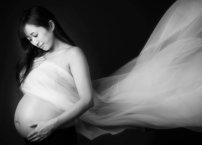 マタニティ：白いチュールの生地がなびいた美しいモノクロマタニティフォト。