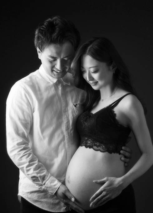 マタニティ：モノクロフォト。ママの大きなお腹に優しく手を添えるパパとママとのツーショット