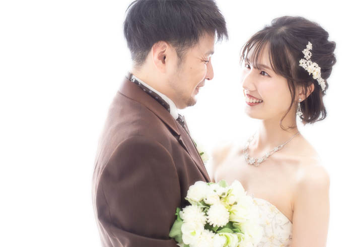 ウェディング：ドレスとタキシードを着た夫婦が仲良く寄り添う様子