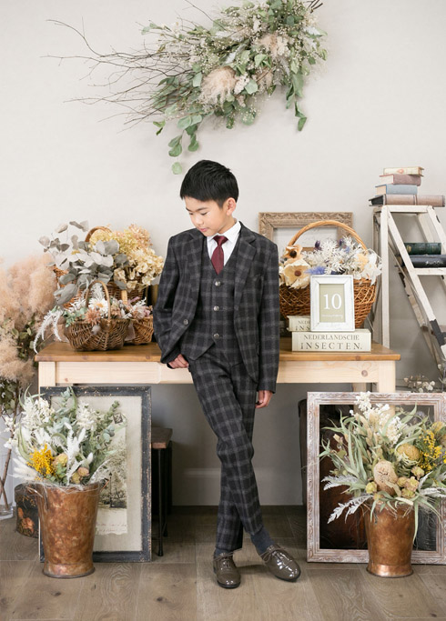 ハーフ成人：チェック柄のスリーピーススーツを着てポージングをする10歳男の子