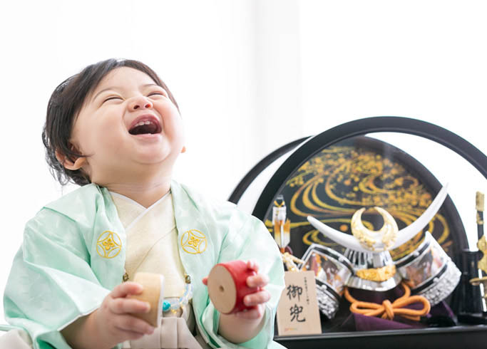 端午の節句：兜飾りと並び大笑いした小さな男の子。