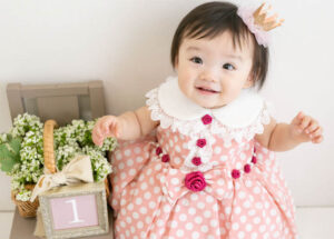 ベビー・バースデー：ピンクの水玉ドレスを着た1歳のかわいい女の子のお誕生日フォト。