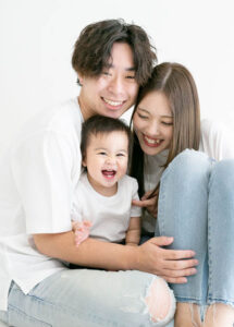 ベビーバースデー：白Tシャツにデニムのお揃いコーデで身を寄せ合い笑うパパママと男の子の赤ちゃん