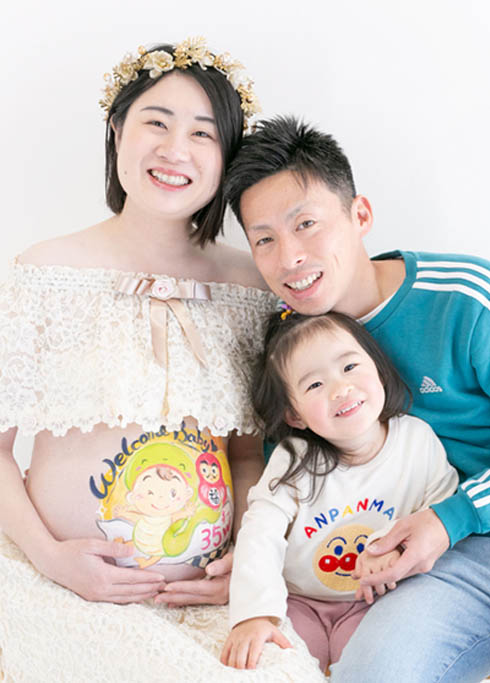 マタニティベリーペイント：かわいいイラストが描かれたマタニティのママとパパと女の子の家族写真。