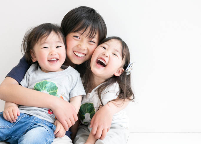ファミリーフォト：お兄ちゃんが小さな弟と妹を抱きしめた温かい兄弟フォト。
