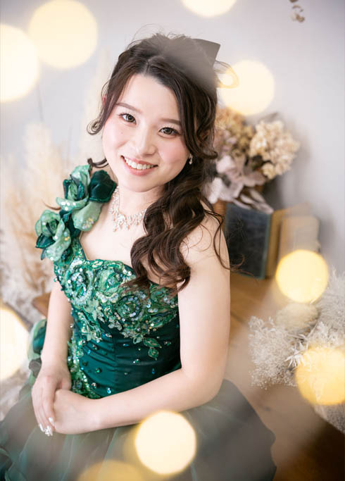 成人：前撮りで濃い緑色のドレスを着てポージングをする二十歳の女性