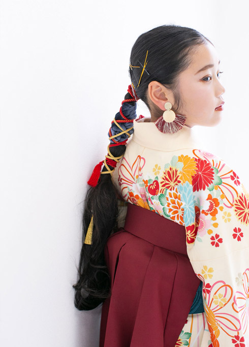 ハーフ成人：薄黄色の古典柄の着物に赤い袴を合わせ、長い髪をタイトに結んだ10歳女の子