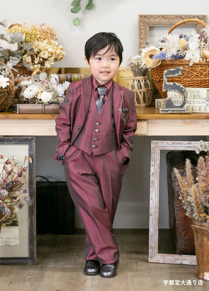 七五三５歳スーツ：光沢のあるえんじ色のスーツを着た5才の男の子。