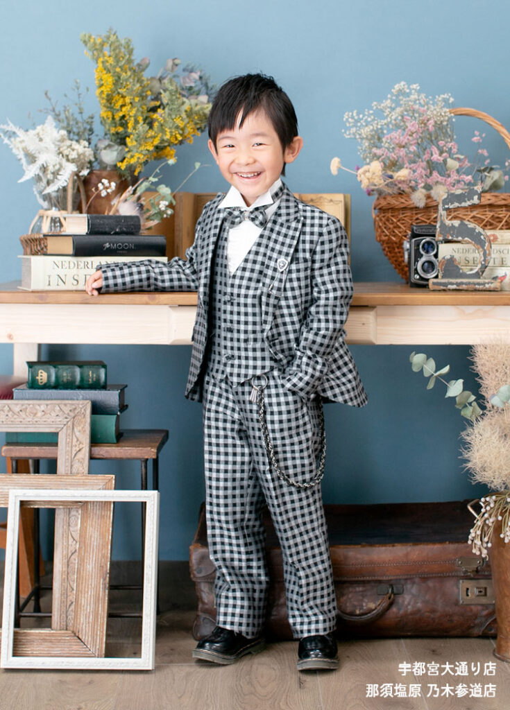 七五三５歳スーツ：光沢のある黒のチェック柄のスーツを着た5才の男の子。
