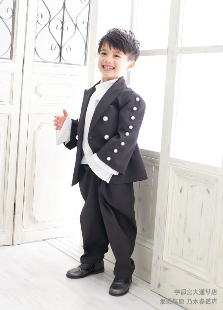 七五三５歳スーツ：フリルシャツとパールの付いたドレッシーなスーツを着た5才の男の子。