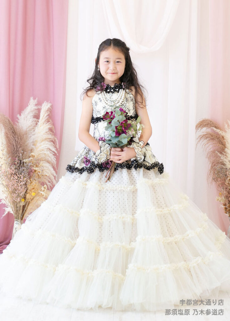 七五三７歳ドレス：白に黒の水玉柄の豪華なドレスを着た7才の女の子。