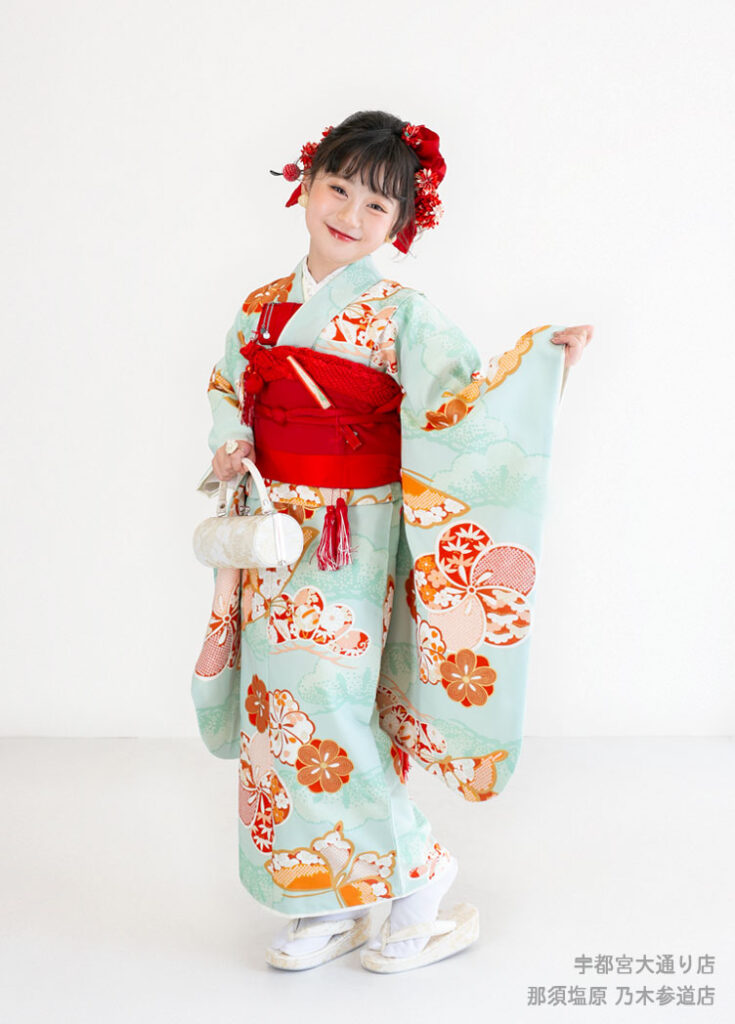 七五三７歳着物：淡いエメラルド色にオレンジの花模様の着物を着た７才の女の子。