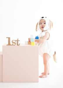 ベビー・バースデー：わんこの着ぐるみを着てつかまり立ちをする1才の男の子。