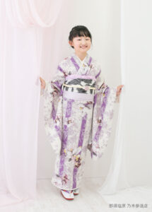 10歳着物：白地に紫のグラデーション縦じまに花模様の着物を着た10才の女の子。