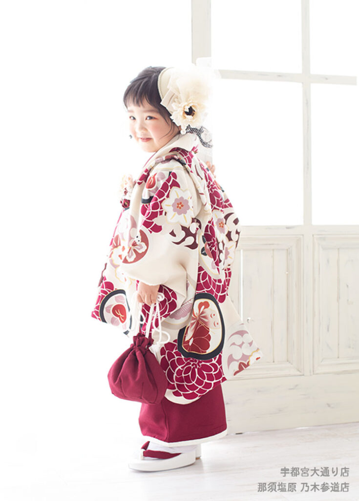 七五三３歳：エンジの和柄の被布コート着物を着た3才の女の子。