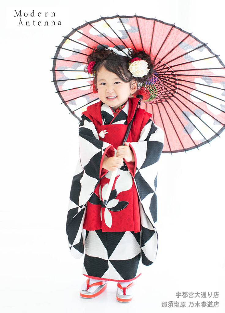 七五三３歳：紅色がアクセントになっているモノトーンの着物を着た３才の女の子。