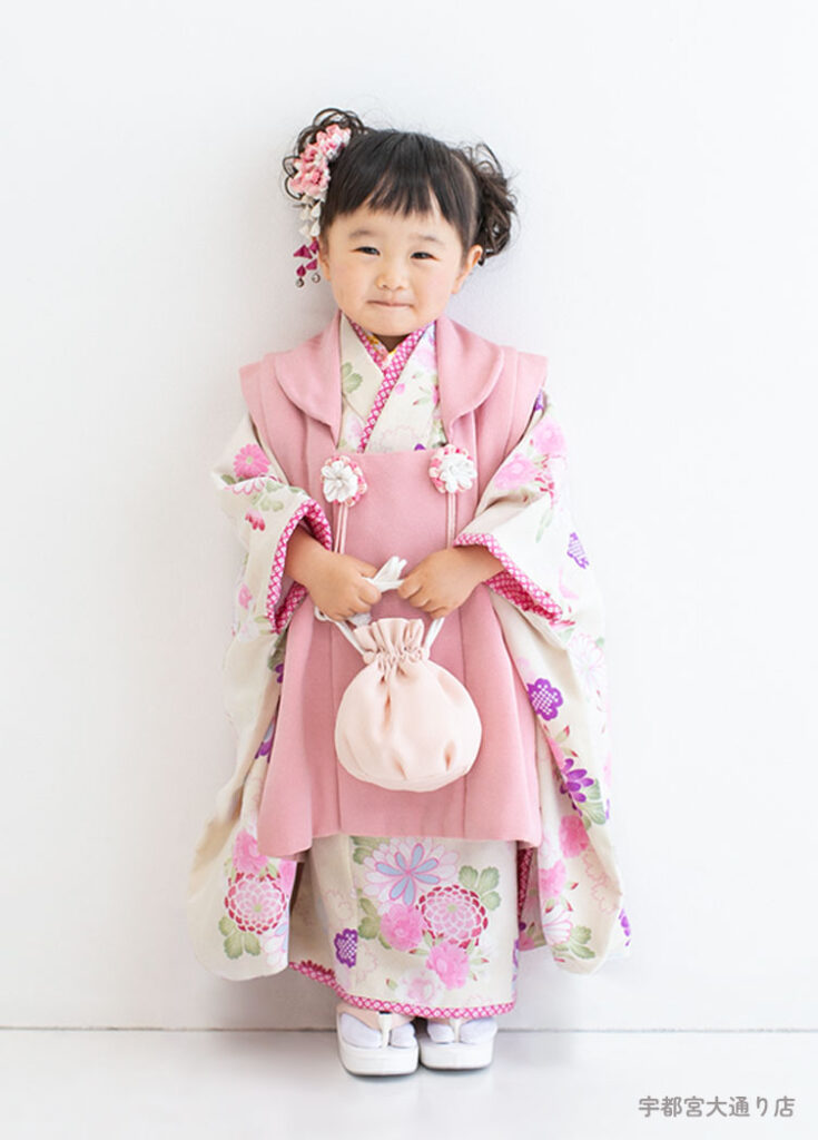 七五三３歳：ベージュの着物にピンクの被布を合わせて今っぽいくすみカラーでそろえた3才の女の子。