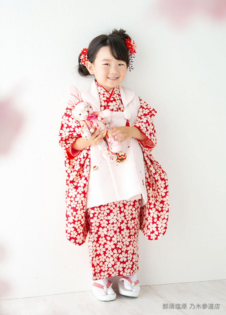七五三３歳：赤い小花柄に白い被布の着物を着た3才の女の子。