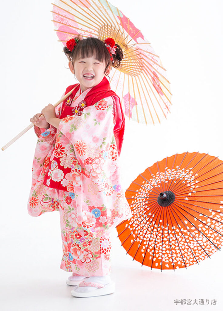 七五三３歳：ピンクの花柄に赤い被布の着物を着た3才の女の子。
