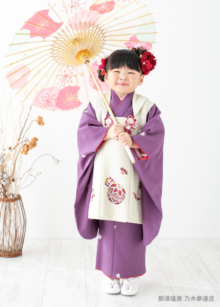 七五三３歳：くすみパープルの着物に乳白色の被布を着た3才の女の子。