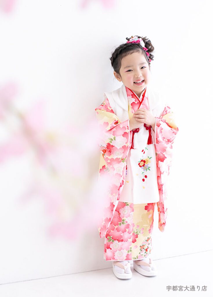 七五三３歳：淡い黄色の生地の中に桜柄が美しい春らしい着物を着た3才の女の子。