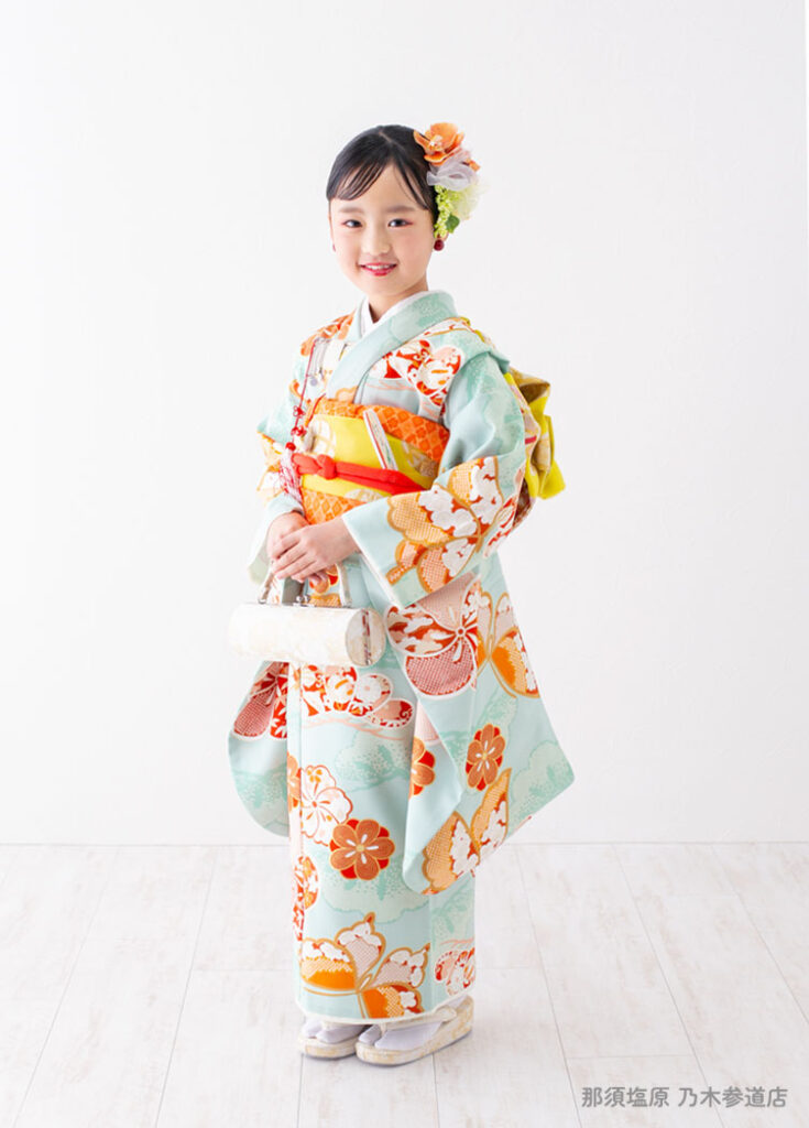 七五三７歳着物：エメラルドにオレンジの花模様の着物を着た７才の女の子。
