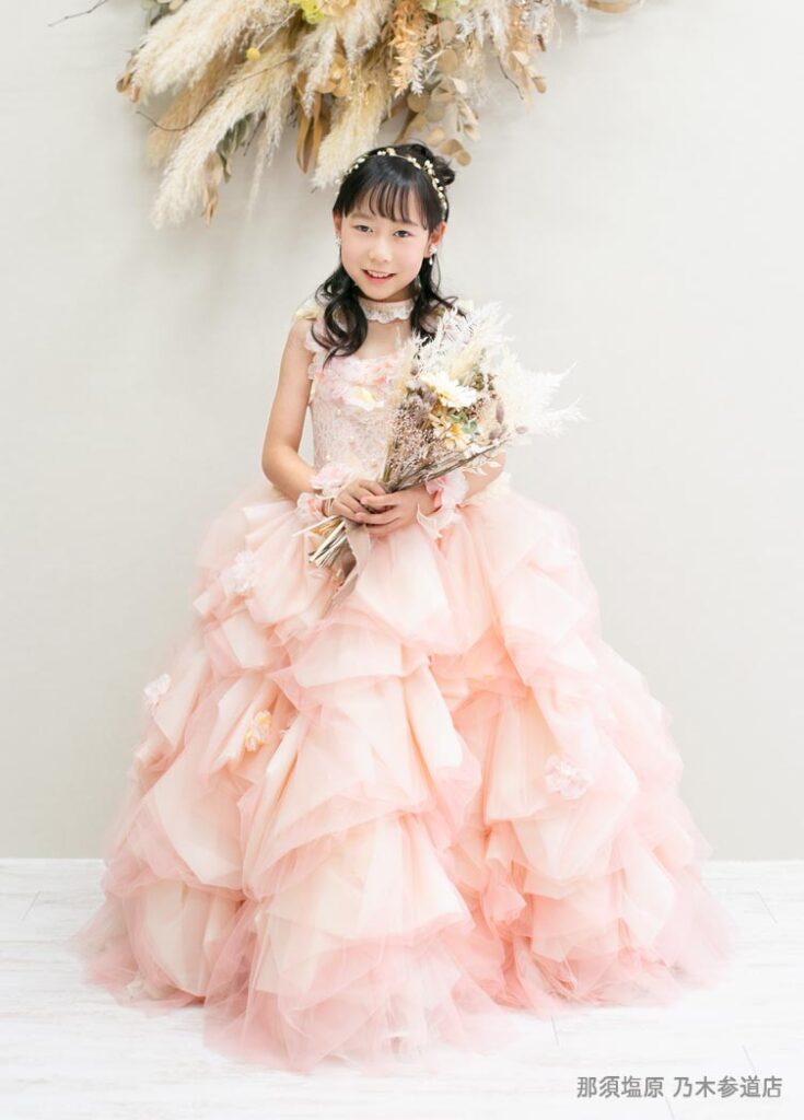 七五三７歳ドレス：コーラルピンクのボリュームドレスを着た7才の女の子。