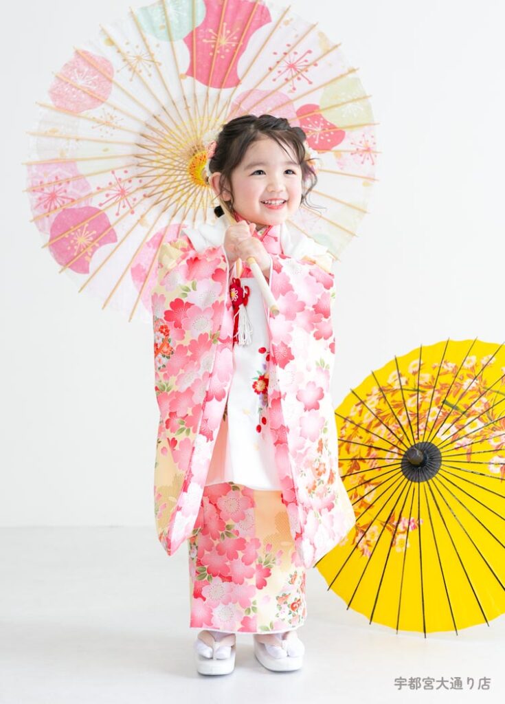 七五三３歳：淡い黄色の生地の中に桜柄が美しい春らしい着物を着た3才の女の子。